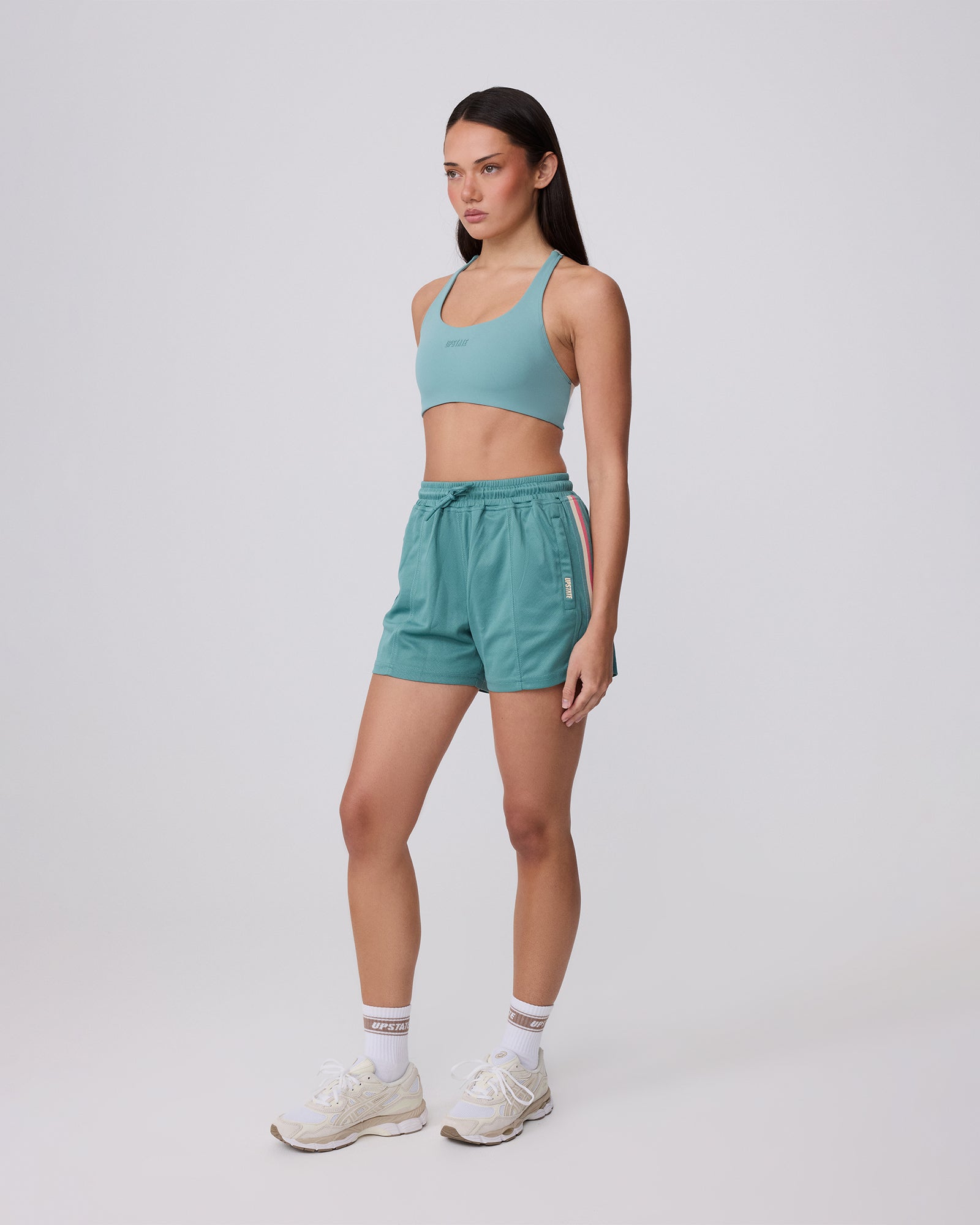 Woman wearing a teal athletic outfit on a white background