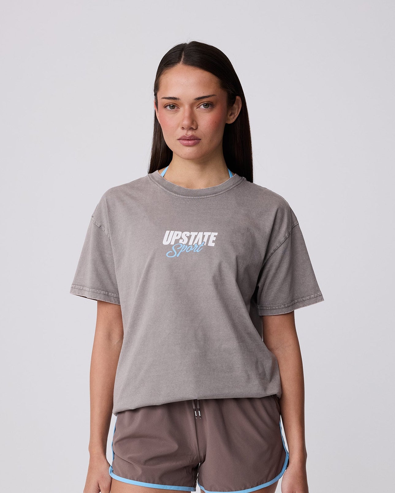 Woman wearing a gray t-shirt and shorts with 'Upstate' branding on a white background