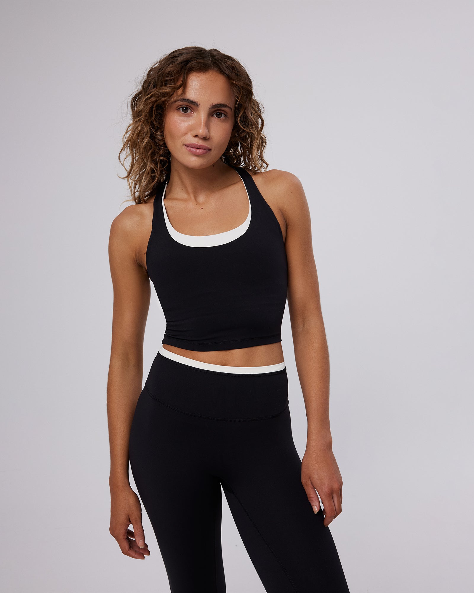 Woman wearing a black sports bra and leggings on a gray background