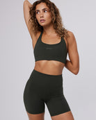 Woman wearing a black sports bra and shorts set on a light gray background