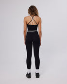 Person wearing a black athletic outfit with white socks on a light gray background